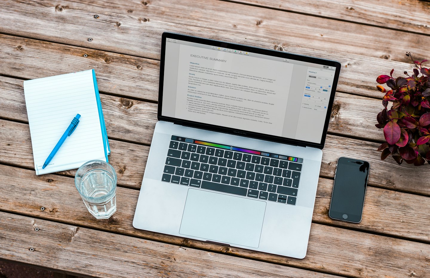 Laptop and office supplies on a wooden deck.