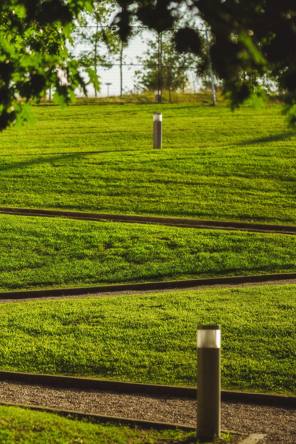 Three parallel gravel paths cut through a manicured green lawn.